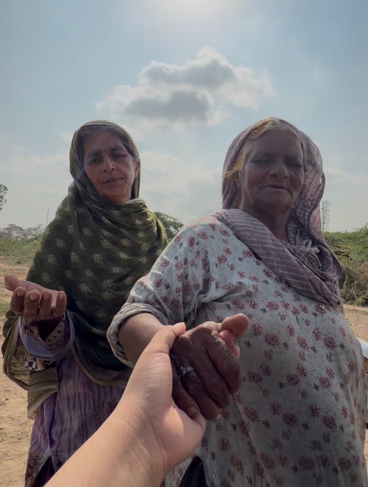 A volunteer holding a woman’s hand, with another woman beside her