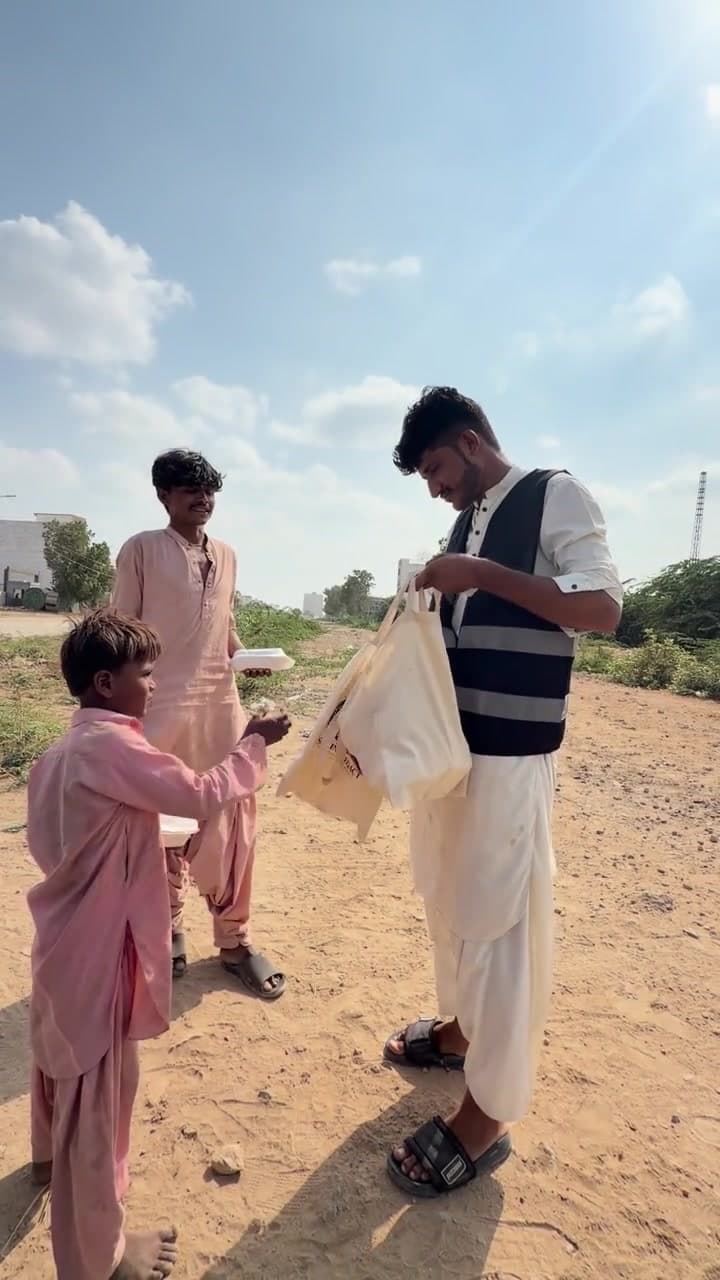 A Sakina Legacy volunteer handing meals to boys on the open ground