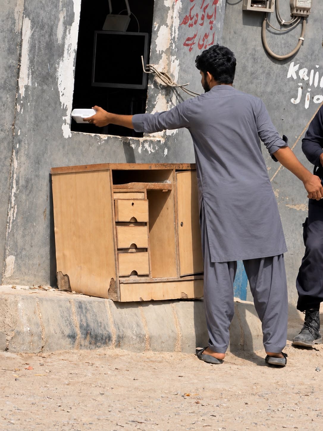 A volunteer passing a meal box through a window to someone inside