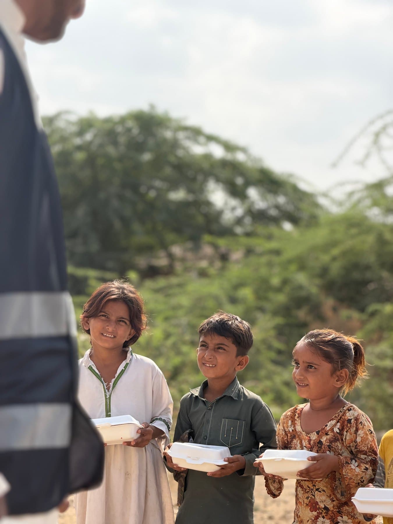 A Sakina Legacy volunteer with children holding their meal boxes