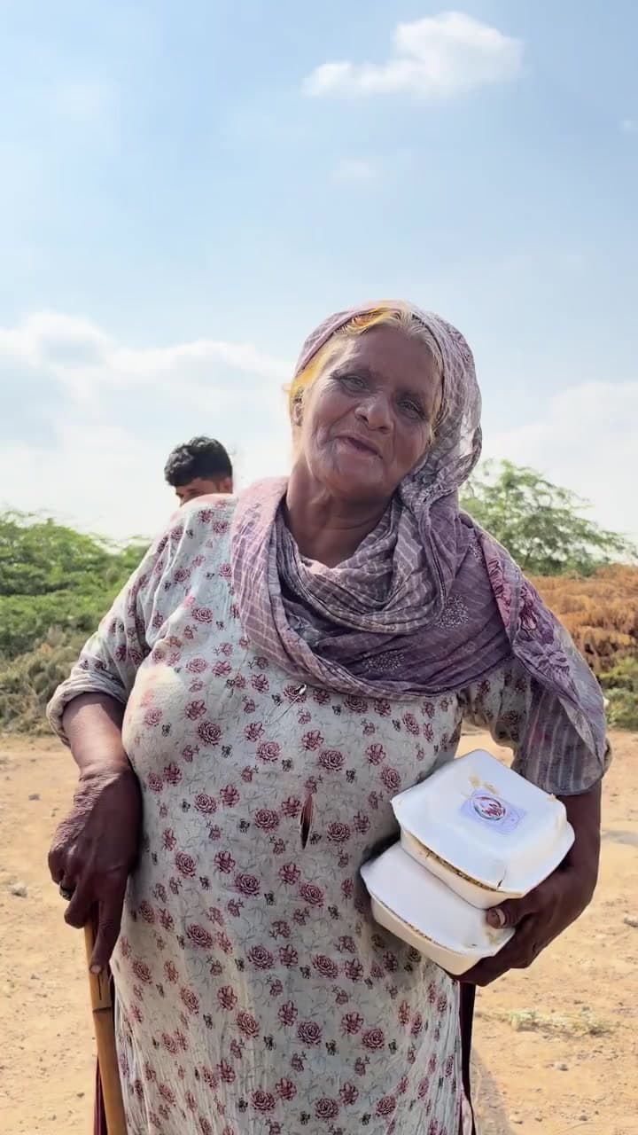 A woman holding two Sakina Legacy meal boxes beside her walking stick