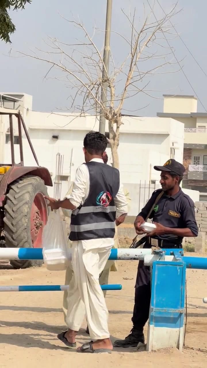 A volunteer and a worker holding a meal beside the roadside barrier